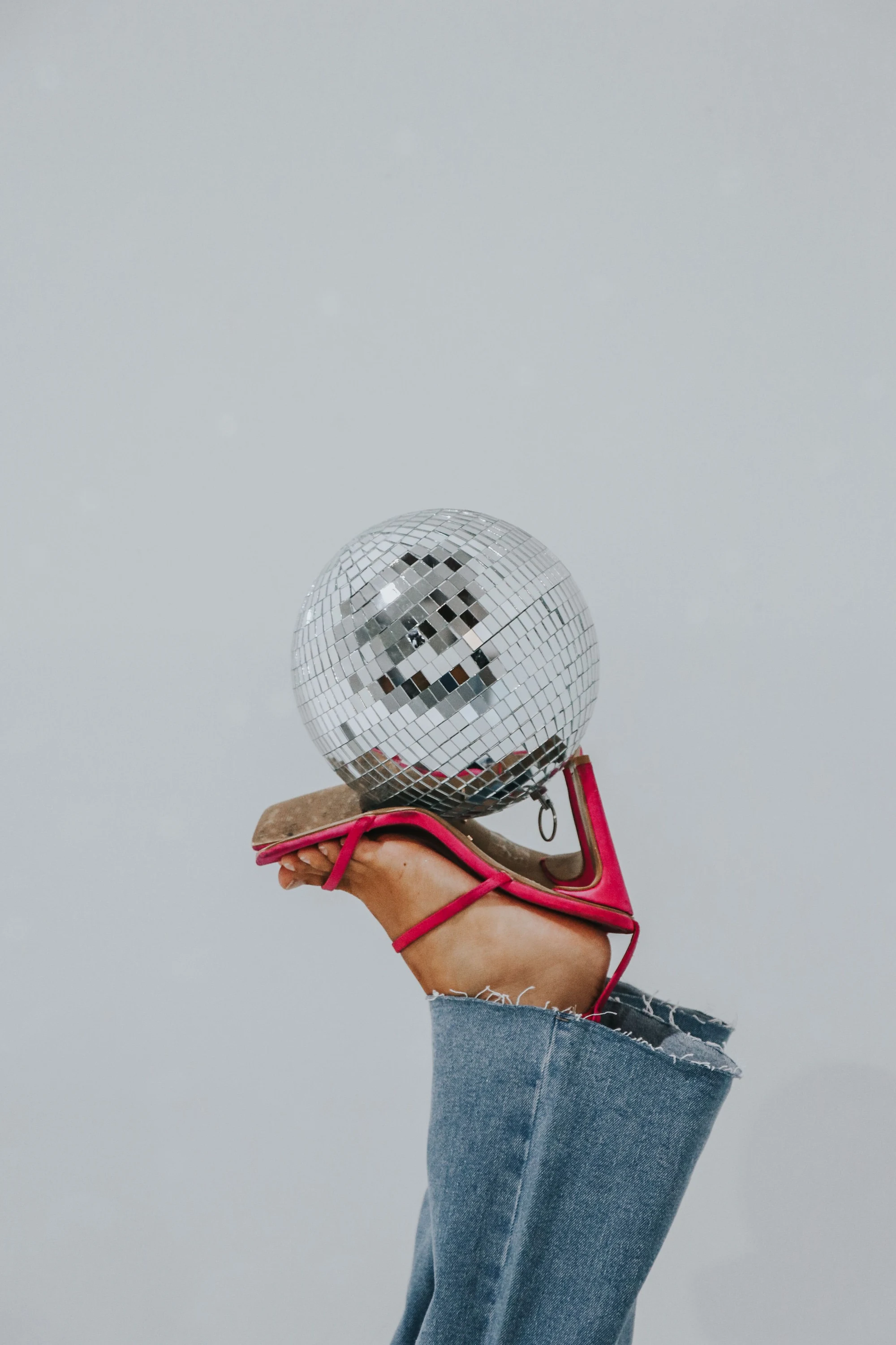Pink heels balancing a mirrored disco ball